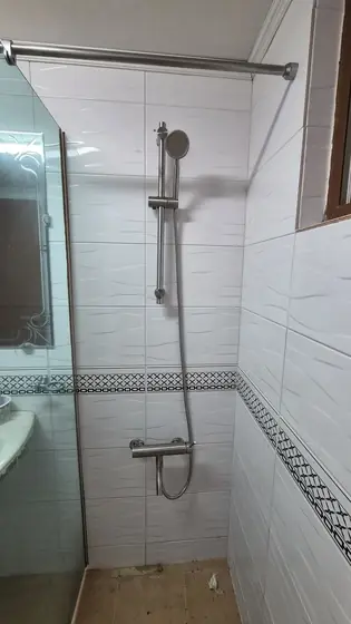 화장실 샤워기 수전 교체 — 새 수전과 샤워기 막대를 단 샤워 공간